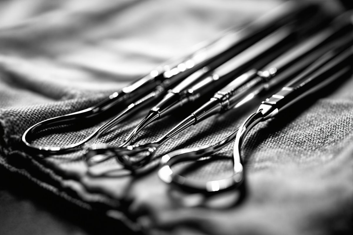 Polished steel dental instruments lined up on a sterile cloth, raking light
            picking out each one.